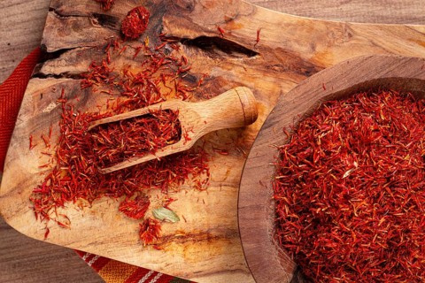Spice saffron threads, in a wooden bowl, on a wooden table, top view, close-up