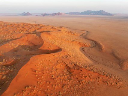 Sand dunes and isolated mountain ridges at the edge of the Namib Desert. Aerial view. Drone shot.