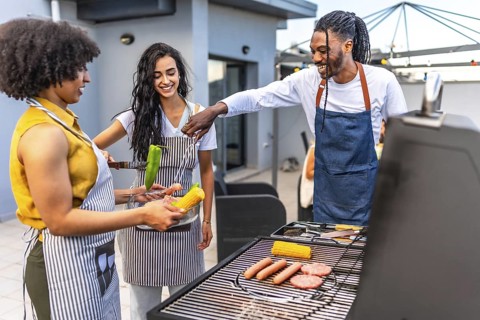 Chefs grilling delicious meats, sausages, corn, and peppers for a lively barbecue party on a