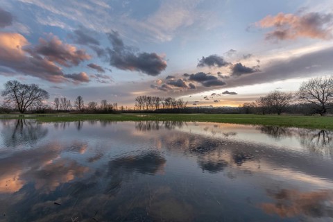 Een serene natuurweergave met een rustig meertje waar de lucht prachtig op het water reflecteert.