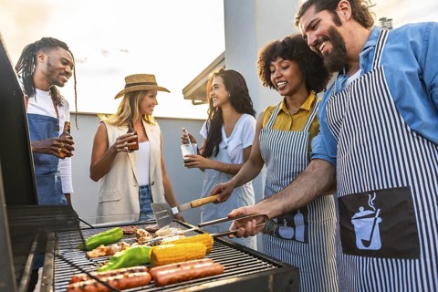 Chefs grilling delicious meat and vibrant vegetables while enjoying cold beer on a rooftop during a