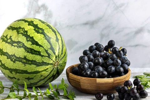Watermelon with a bowl of grapes and mint in a bright setting