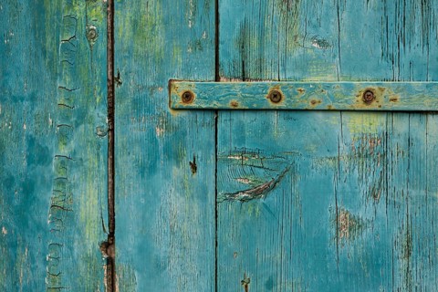 Weathered green wooden door with rusty metal accents in rustic style, background, texture,