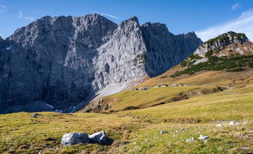 Rocky mountain ridge with summit Grubenkarspitze and Dreizinkenspitze, in front of it alpine huts
