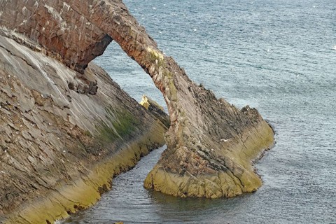 Remarkable rock formation jutting into the sea under a blue sky with few clouds, Bow Fiddle Rock,