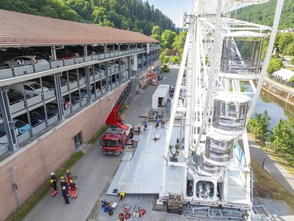 Fire engines and workers next to a Ferris wheel in an urban environment, fire brigade exercise for