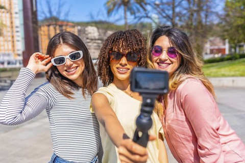 Multi ethnic women enjoying summer urban vacation, using action camera to film themselves,