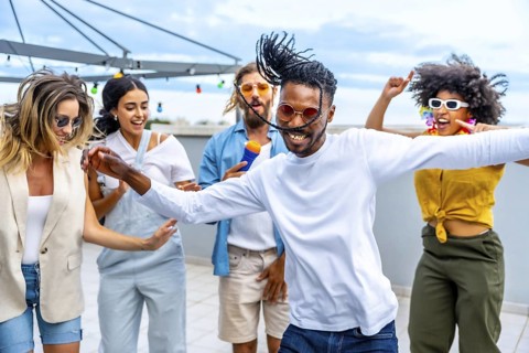 Young people dancing and singing joyfully at a vibrant rooftop party, enjoying music and
