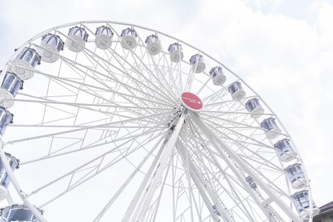 Large Ferris wheel with white gondolas and a sunny sky as a backdrop, Ferris wheel construction,