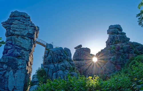 The morning sun shines through an opening in the Externsteine. The Externsteine, a sandstone rock