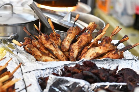 Grilled Thai chicken skewers on display at street food market. Traditional gai yang with wooden