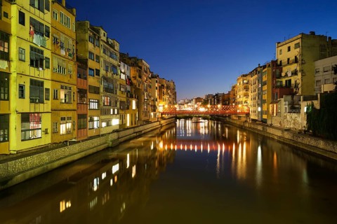 Girona city by night in Spain, waterside houses on the River Onyar, picturesque urban landscape in