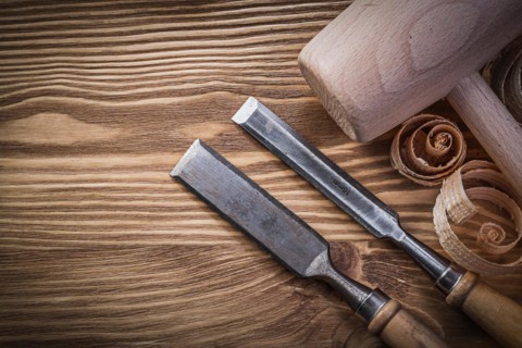 Carpenter's chisel and shavings on wooden board