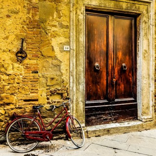 Red bicycle leaning against a wall in Pienza