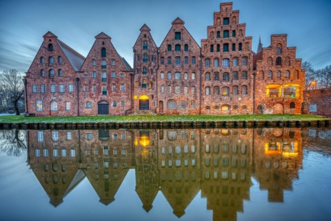 The historic salt warehouse reflected in the Trave river at dusk, seen in Lübeck, Germany