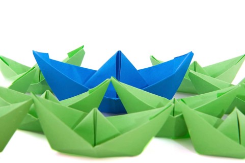 Gren paper boats with one blue ship