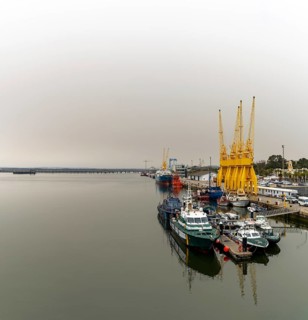 Huelva, Spain - 15 March, 2022: calm Rio Tinto River with harbor cranes and Guardia Civil police