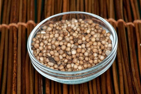 Dried coriander in a bowl on wooden base