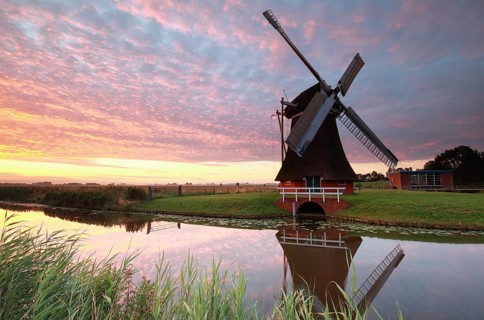Dutch windmill by river at sunrise, Netherlands