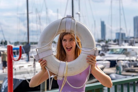 A gorgeous redhead model enjoys the perfect summer weather at a local marina, surrounded by boats