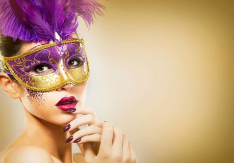 Beautiful woman with dramatic mekaup and pruple lipstick wearing puprle mask. Light background.