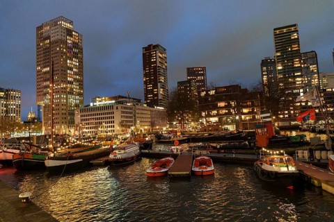 View of the busy harbour with skyscrapers and boats at dusk, Rotterdam, Netherlands