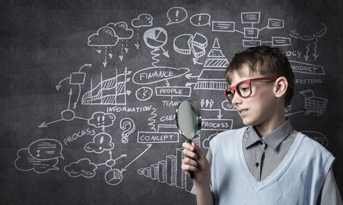 Cute boy looking through magnifying glass against blackboard background