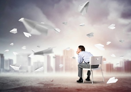Young businessman sits on an office chair, thoughtful and looking up