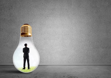 Businessman inside of light bulb in empty concrete room
