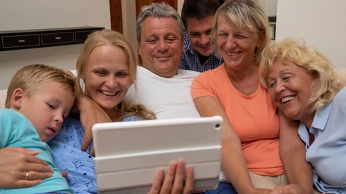 A big family is watching something funny on a pad, close side by side