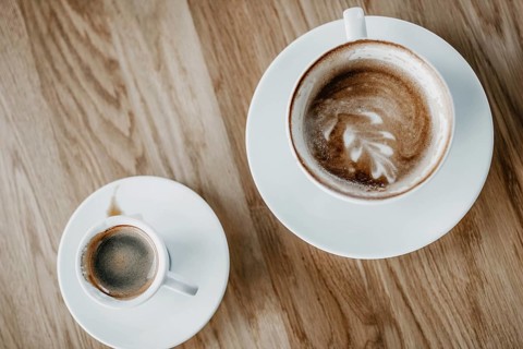 Top view of a cappuccino with latte art and an espresso on a wooden table