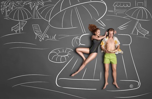 Love story concept of a romantic couple lying on an air mattress against chalk drawings background.