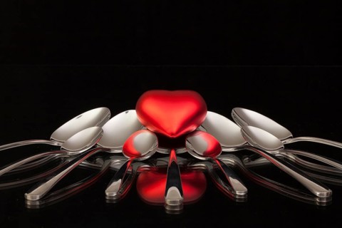 Nine spoons and red heart on a black glass desk