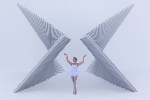 Ballerina poses gracefully between a futuristic sculpture in winter in sub-zero temperatures,