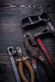 Rusty vintage hacksaw nippers pliers on wooden board construction concept