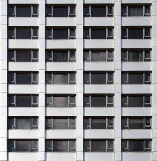 Front view of the facade of a modern commercial building with geometric repeating windows and grey