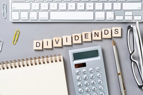 Dividends payment concept with letters on wooden cubes. Still life of office workplace with