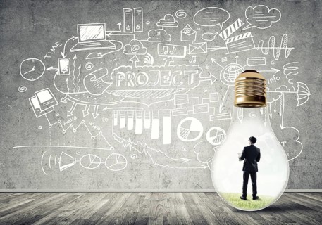 Businessman inside of light bulb in empty concrete room and sketches on wall