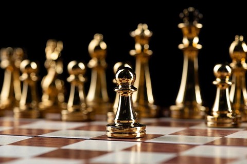 Golden chess figures standing on wooden chessboard. Intellectual duel and tactical battle in