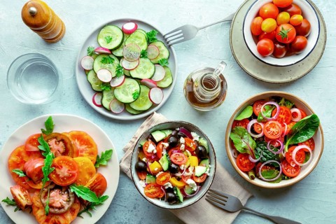 Fresh vegetarian salads, overhead flat lay shot of an assortment. Variety of plates and bowls with