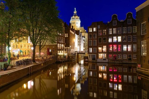 Night view of buildings and boats along the canal in Amsterdam, Netherlands