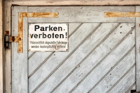 An image of a private no parking sign with german text Illegally parked vehicles will be towed at
