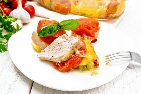 Vegetable casserole with chicken breast, red tomatoes, zucchini and spices in a plate and glass
