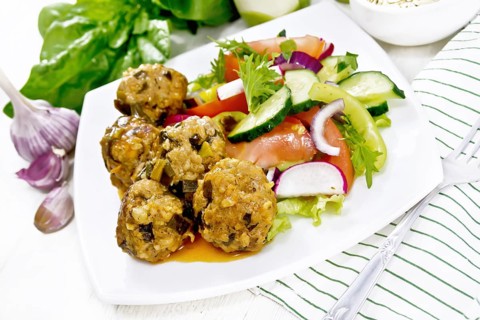 Minced meatballs with spinach, oatmeal and green onions in tomato sauce, vegetable salad in a