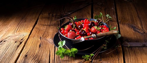 Bowl with different fruits such as strawberry, red currant, and cherry