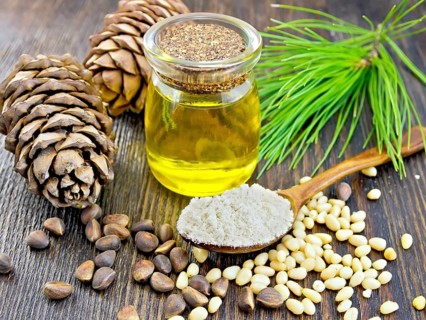 Cedar Flour in a wooden spoon, cedar nuts and two cones, cedar oil in a glass jar, a cedar branch