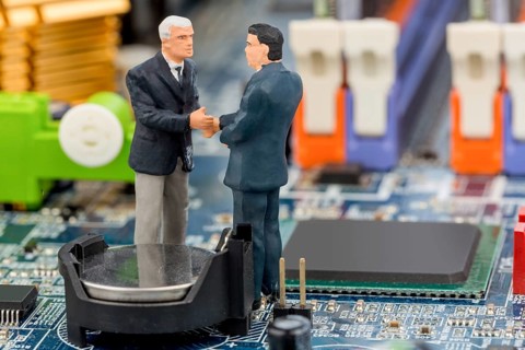 Two managers are having a conversation standing on the circuit board of a computer