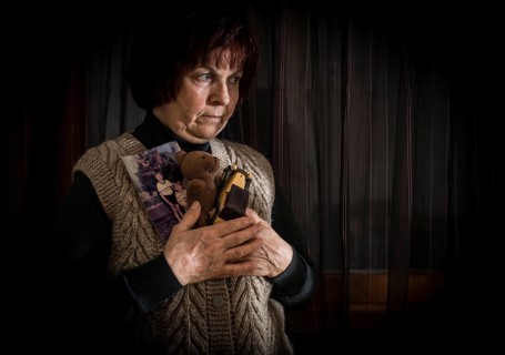 Senior woman hold pictures of childrens. Toys