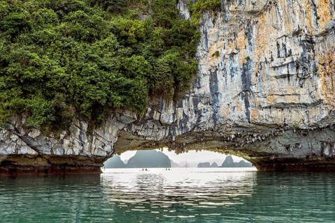 Natural scenery with rock formation over calm water, rock bridge and cave in Halong Bay in Vietnam