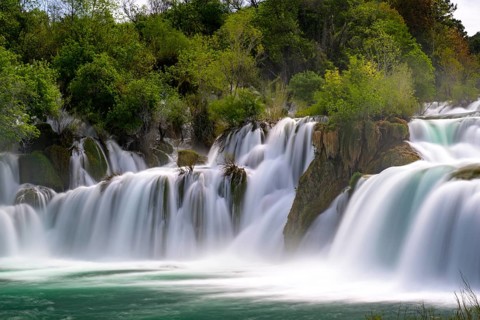 A large waterfall flowing powerfully through trees and rocks, Krka National Park, Krka Waterfalls,